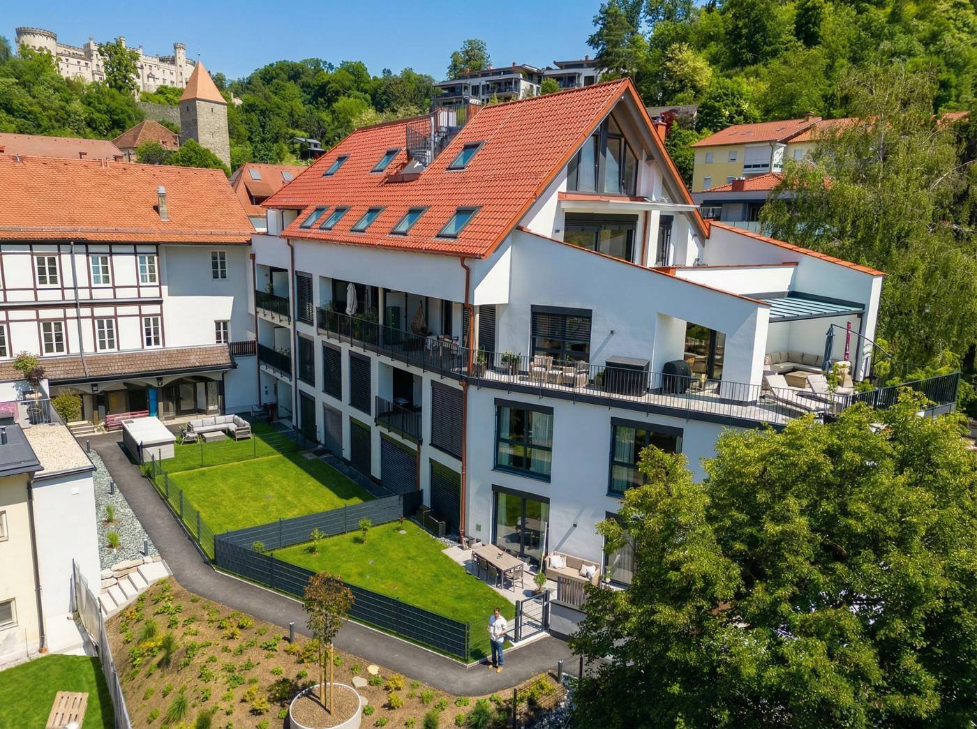 Wohnanlage Moserhof, Luftansicht mit Gärten, Dachterrassen und Burg im Hintergrund